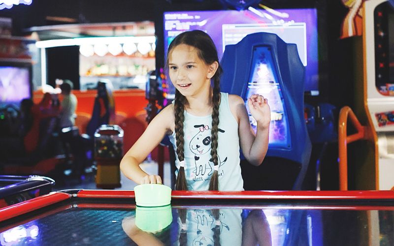 Young girl playing air hockey at the Arena Sports Family Entertainment Center