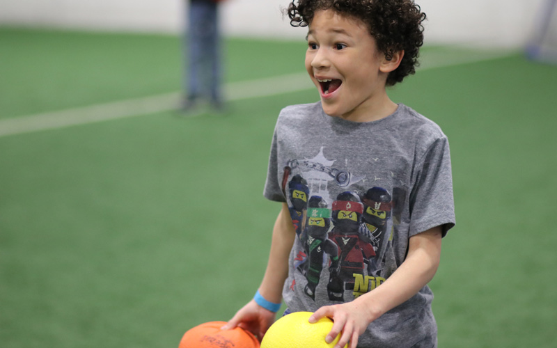 young boy smiling and playing dodgeball