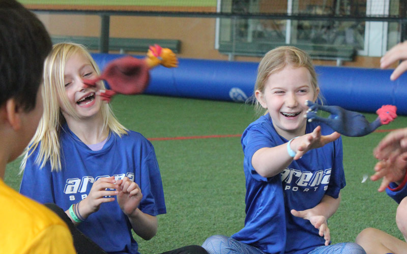 two girls playing camp game with rubber chickens