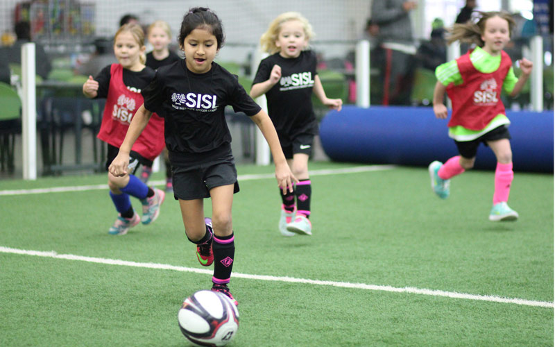 Skills Institute Soccer League game with girl running