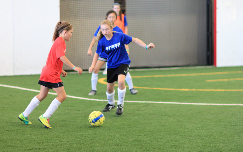 Youth League soccer girls running for a yellow ball