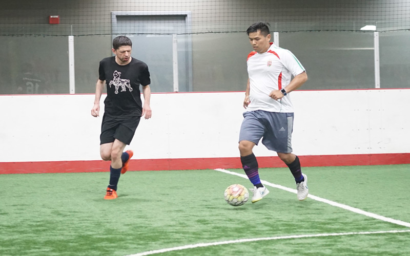 Two men playing adult drop-in soccer with a white soccer ball