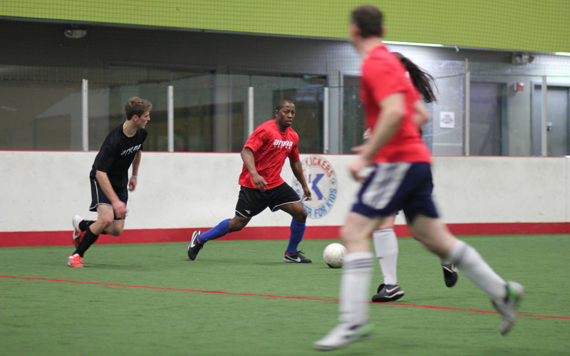 Adult soccer players running toward a white soccer ball Men playing soccer