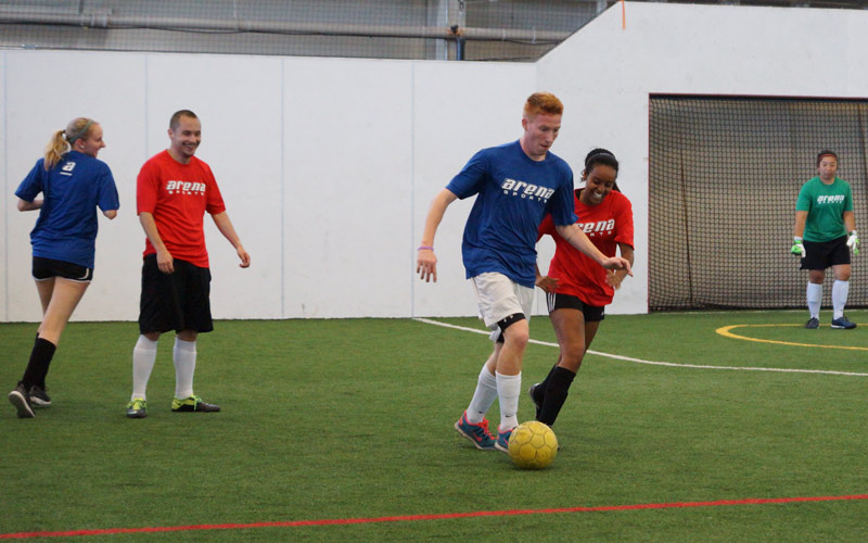 Coed adult indoor soccer players with yellow ball