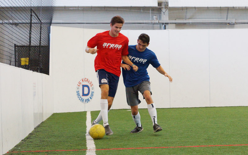 Two men playing adult league indoor soccer