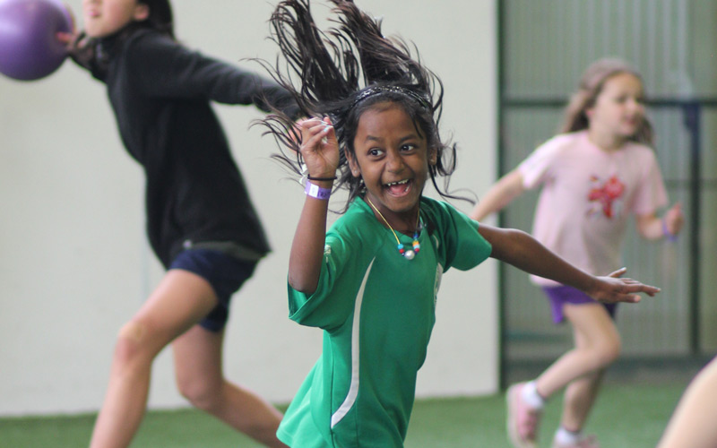 Girl laughing and playing dodgeball at Birthday Parties