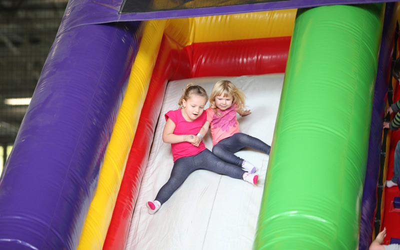 two girls sliding down funzone slide.