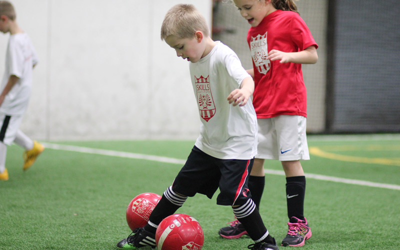Skills Institute Boy Dribbling a Red Soccer Ball