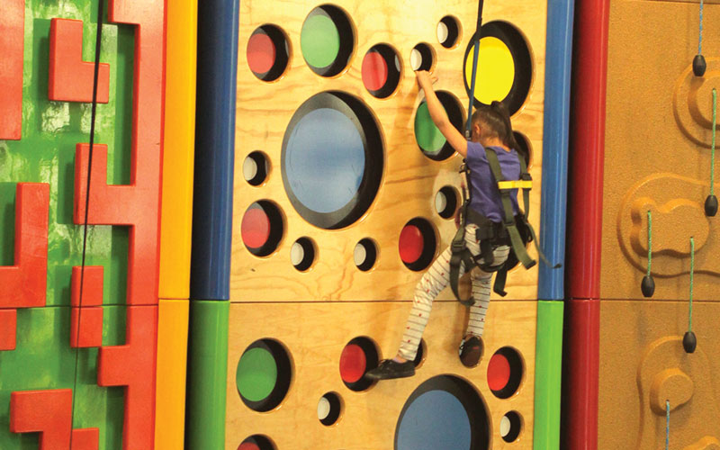 A young girl uses the climbing wall at the Family Entertainment Center at Arena Sports