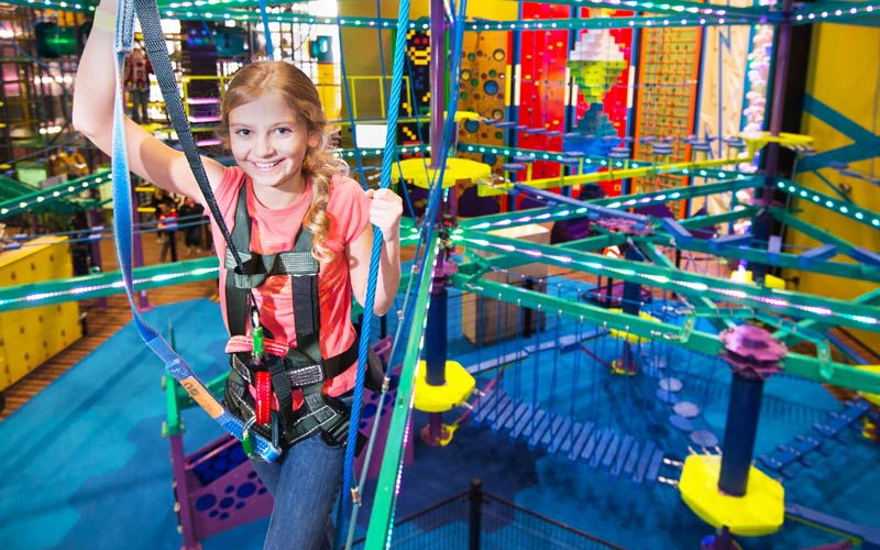 pre-teen boy harnessed on ropes course course