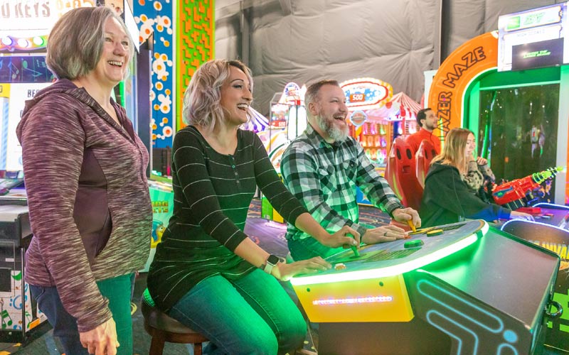 A man and woman play arcade games at Arena Sports Mill Creek