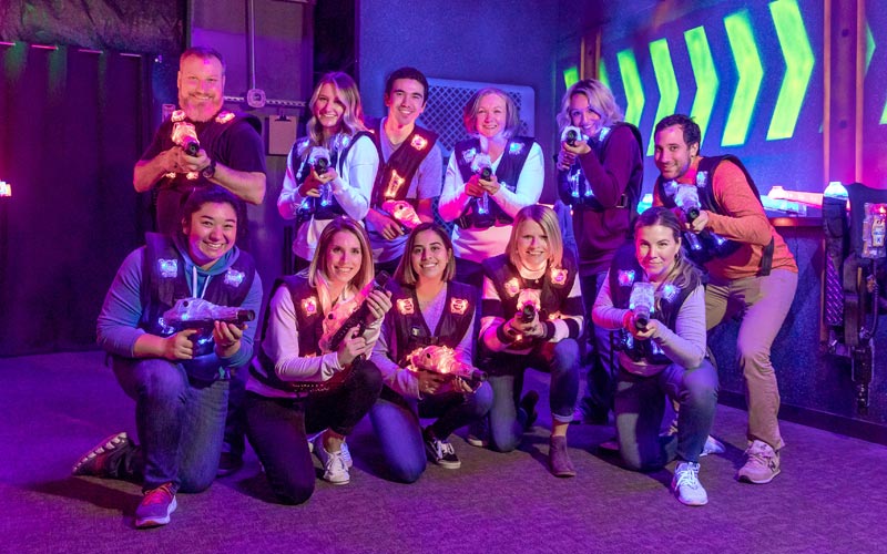 A group of adults pose in the Laser Tag arena during a group event at Arena Sports
