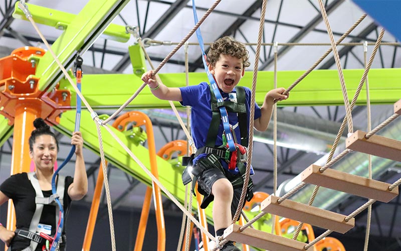 A child laughs while on the ropes course at the Family Entertainment Center at Arena Sports