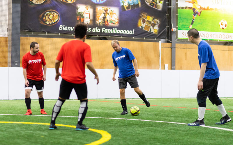 Adult soccer players running toward a white soccer ball