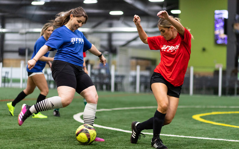 Coed adult indoor soccer players with yellow ball