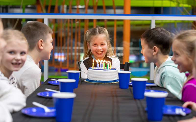Birthday Party girl blowing out candles on cake with friends