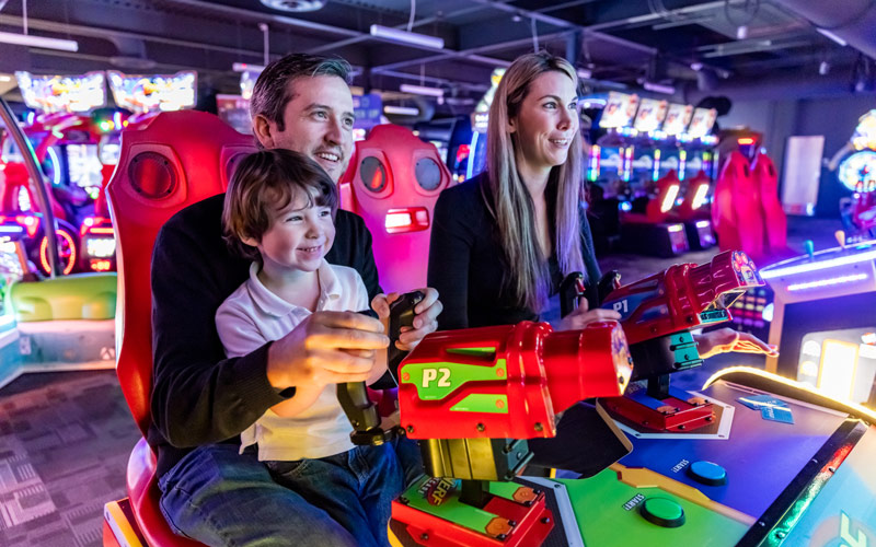 Find things to do in issaquah - A man, woman and child enjoy family entertainment playing games in the arcade at Arena Sports in Issaquah