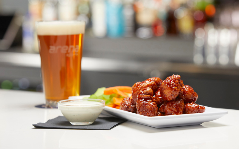Arena-Sports-Restaurant-BBQ-Boneless-Wings BBQ boneless wings with carrots and celery, served with a beer.