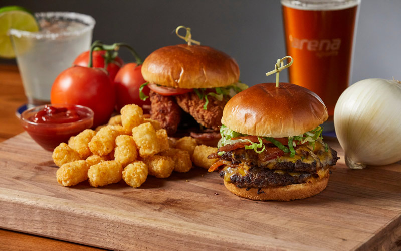 Double cheeseburger and a chicken sandwich served with tater tots on a wood block