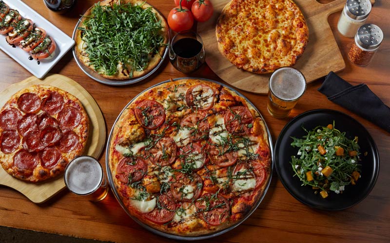 Pizzas, salads, beer and wine served on table