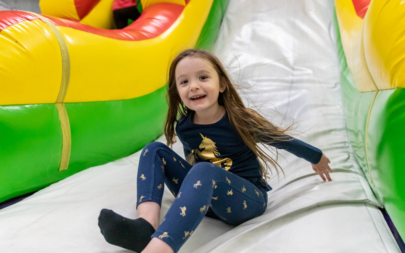 A little girl smiles on the Inflatable FunZone attraction in the Family Entertainment Center at Arena Sports