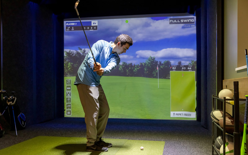 A man plays golf in the Sports Simulator Lounge at the Family Entertainment Center at Arena Sports