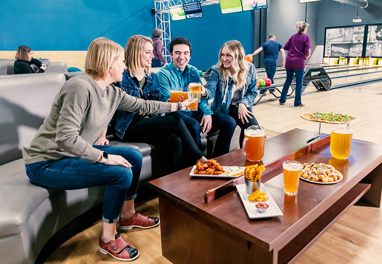 Group of people having pizza and beverages at the bowling alley in Arena Sports