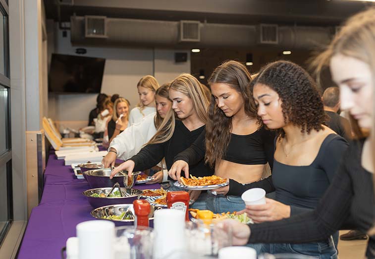 A group of teenage girls select food from the buffet during a group event at Arena Sports