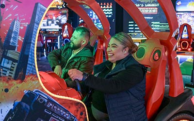 Man and woman play driving game in the arcade during a corporate event at Arena Sports