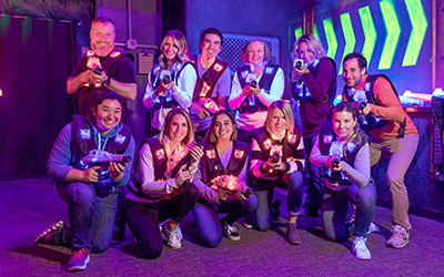 A group of people pose in the laser tag arena at Arena Sports, a great event venue for your next corporate event