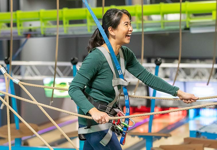 A woman navigates the ropes course during an event at Arena Sports