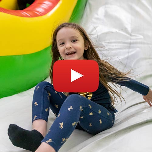 Youtube Play Button icon on an image of a girl in the Inflatable Funzone
