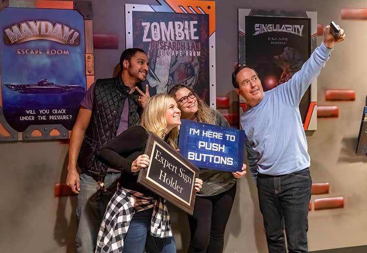 Four adults pose for a photo outside the escape rooms at Arena Sports