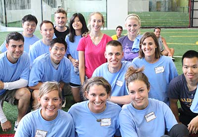 Group of adults smile and pose on the indoor soccer fields during a Corporate Event at Arena Sports