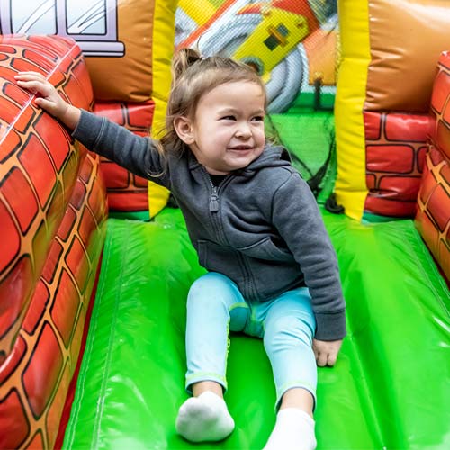 A little girl slides down a bouncy slide at the Inflatable FunZone at Issaquah