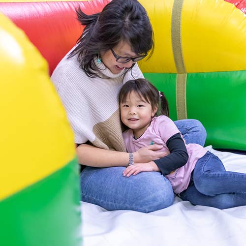 A mother and small child snuggle while playing in the Inflatable FunZone at Arena Sports Mill Creek