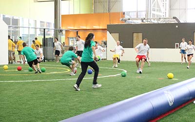 Adults play kickball on the turf field during a Corporate Event at Arena Sports