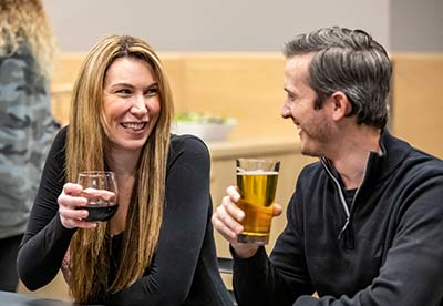 A man and woman smile while having a drink during a corporate event at Arena Sports