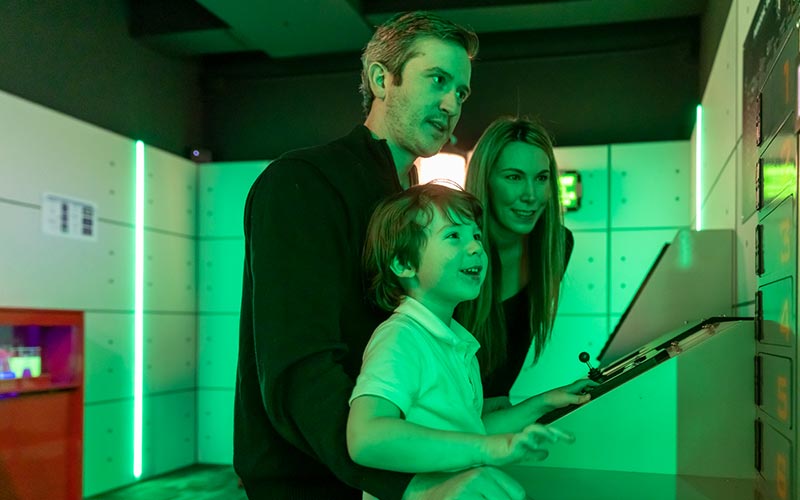 Two parents and a child read a clue in an Escape Room at Arena Sports Issaquah
