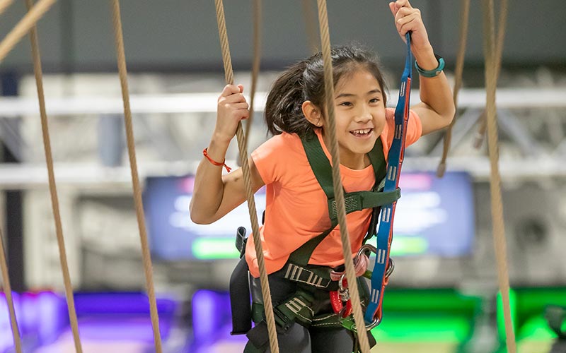 A girl smiles while on the ropes course at Arena Sports