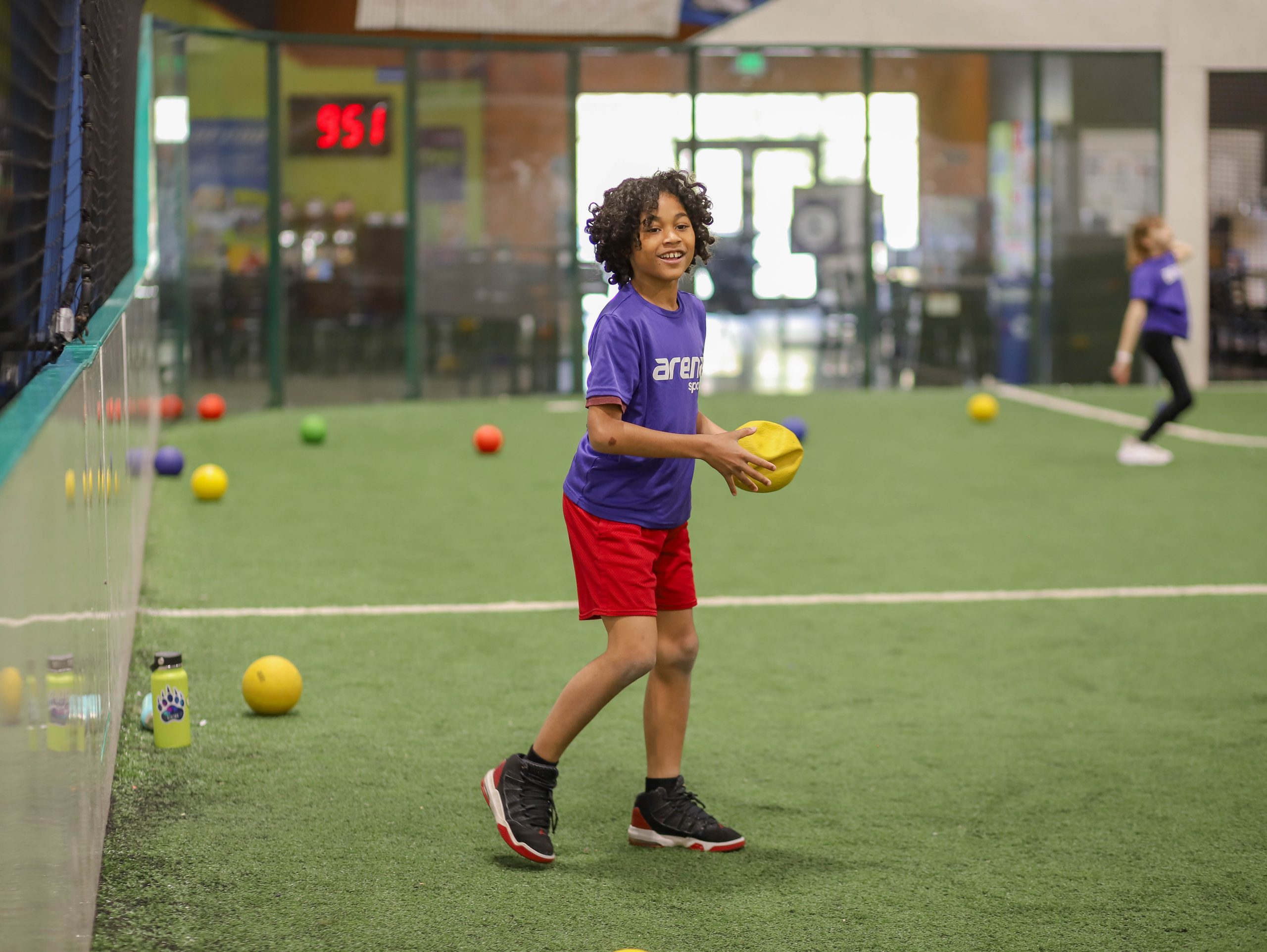 A child holds a dodge ball during camp at Arena Sports