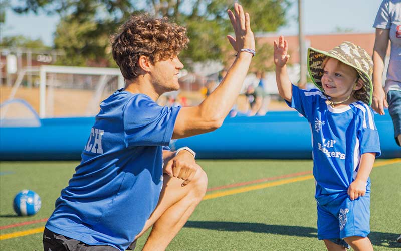 An Arena Sports soccer coach high fives with a young player