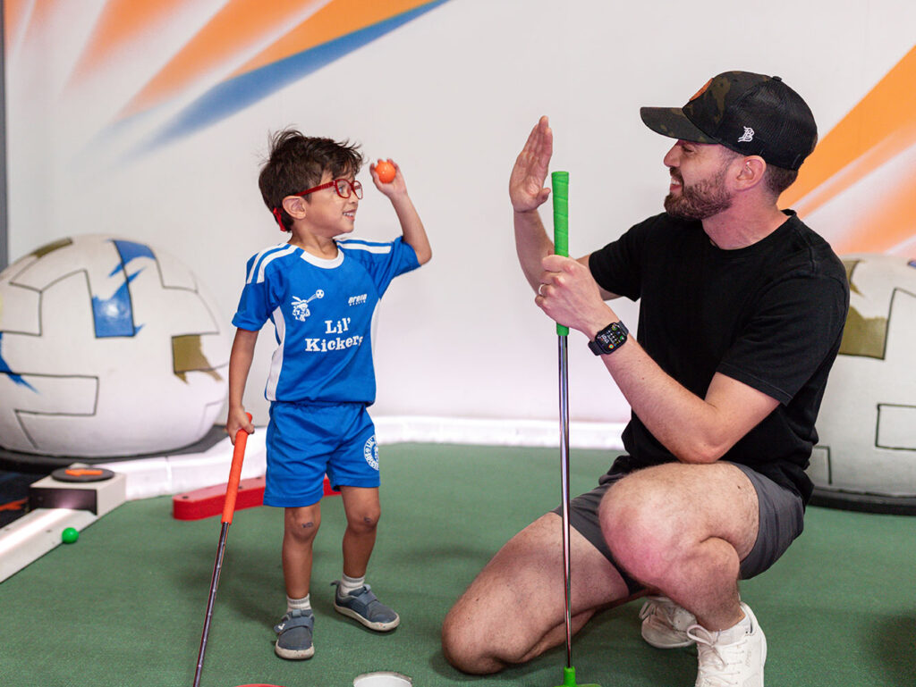 a boy and his dad high five while playing mini golf at Arena Sports