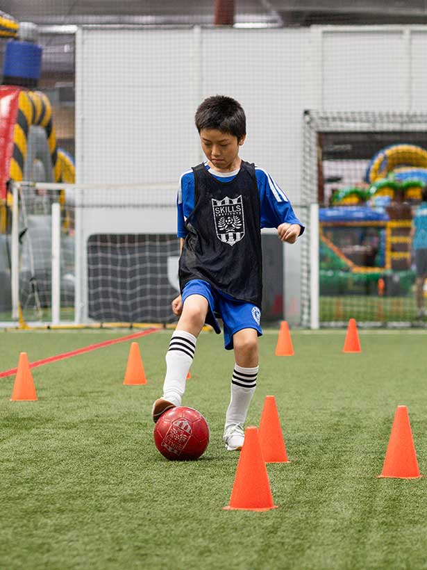 A boy in a soccer uniform practices a drill during Skills Institute camp at Arena Sports