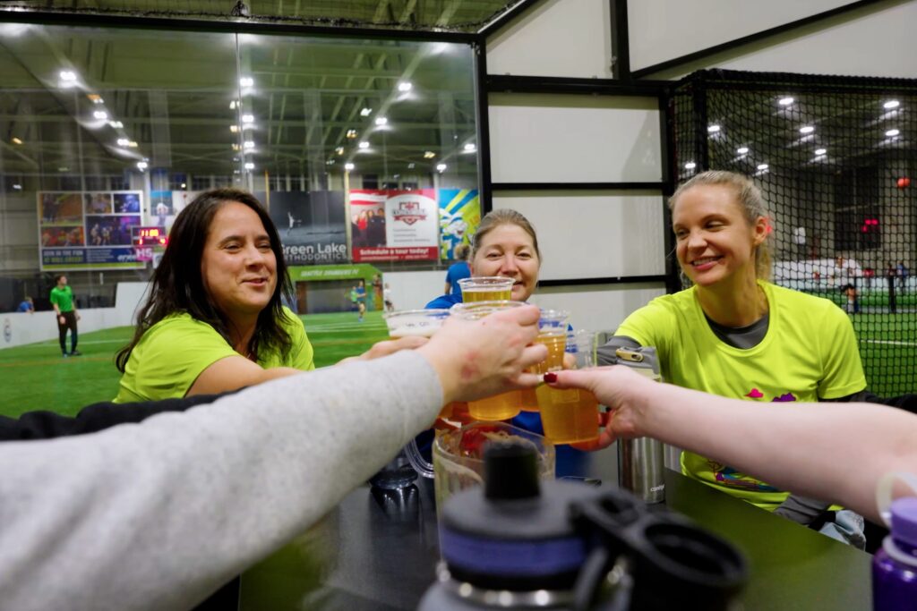 group of ladies cheersing drinks next to a soccer field