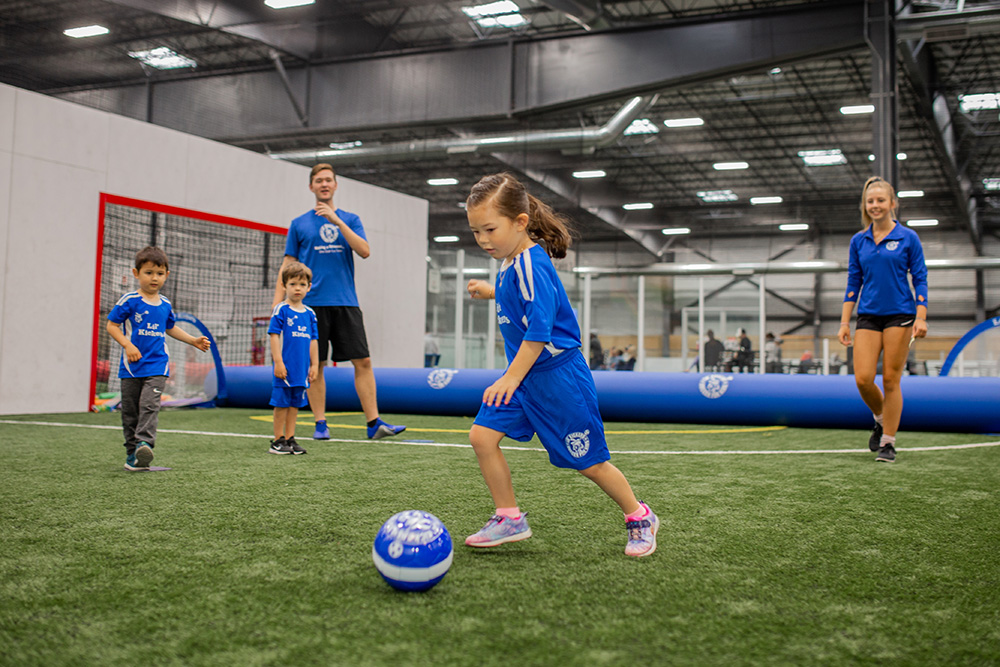 Young girl dribbling a soccer ball during Lil' Kickers classes.