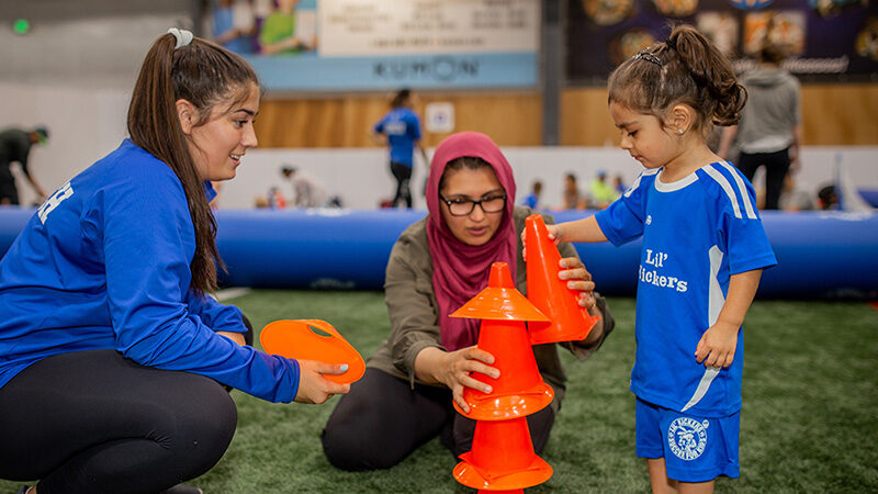 Young girl and mom stacking cones during Lil' Kickers class at Arena Sports.