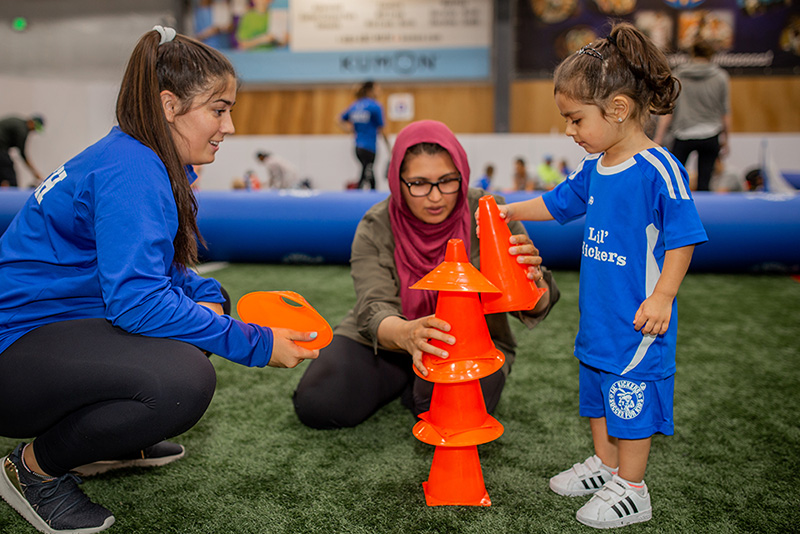 Young girl and mom stacking cones during Lil' Kickers class at Arena Sports.