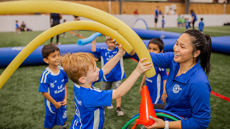Kids playing with coach during Lil' Kickers soccer class.