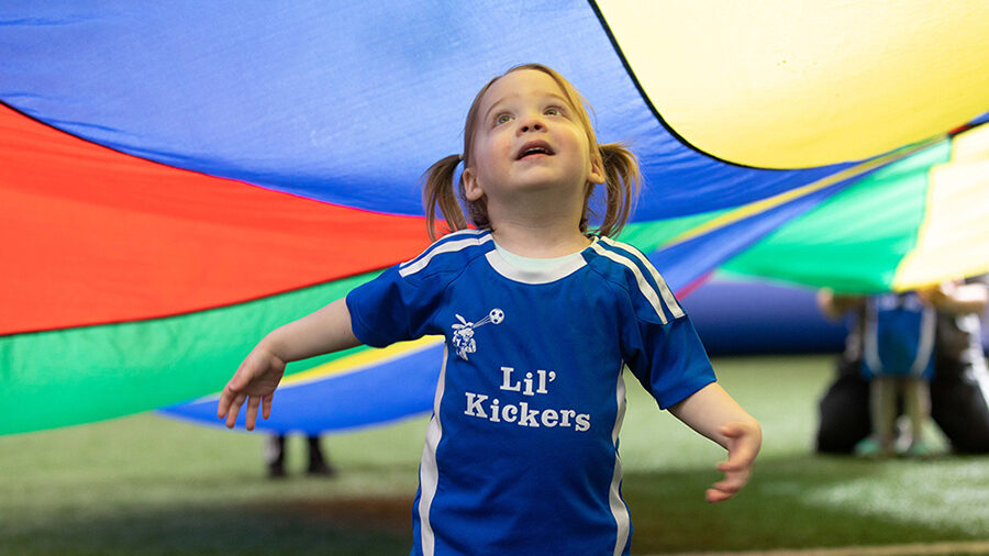 Young girl playing at Lil' Kickers soccer class.